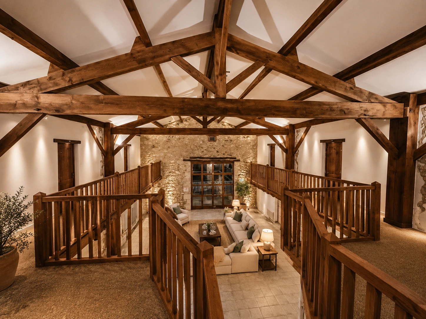 Salle De Commune interior with exposed timber trusses, mezzanine walkways and stone wall